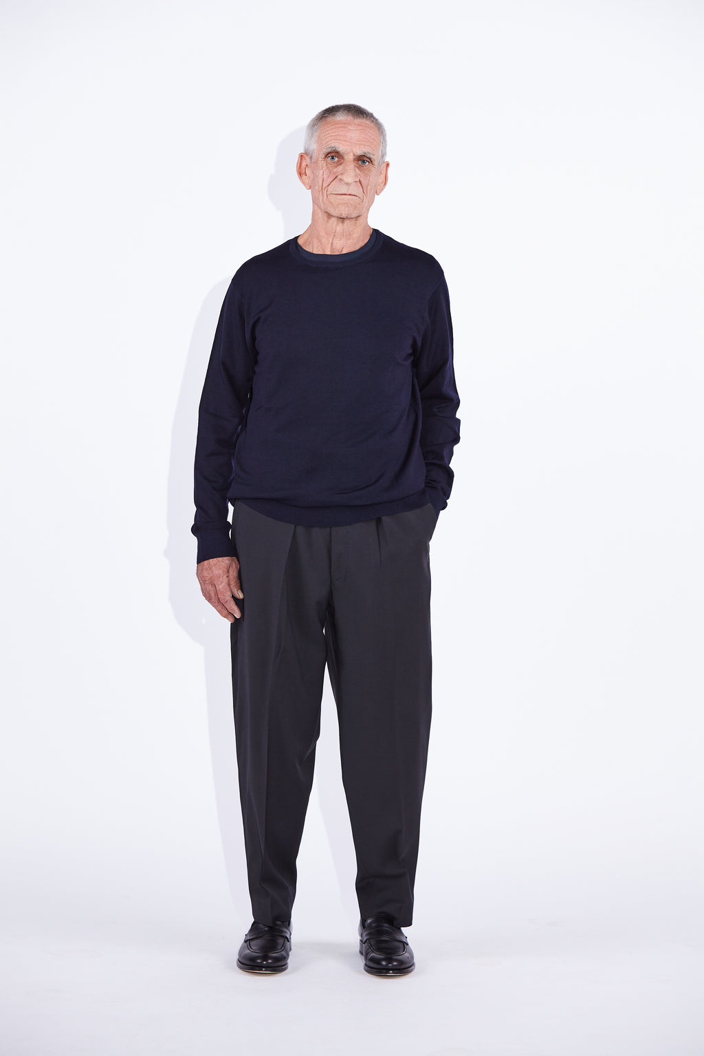 Model wears Casely-Hayford Augustin Navy Merino Wool Crew Neck Jumper. 