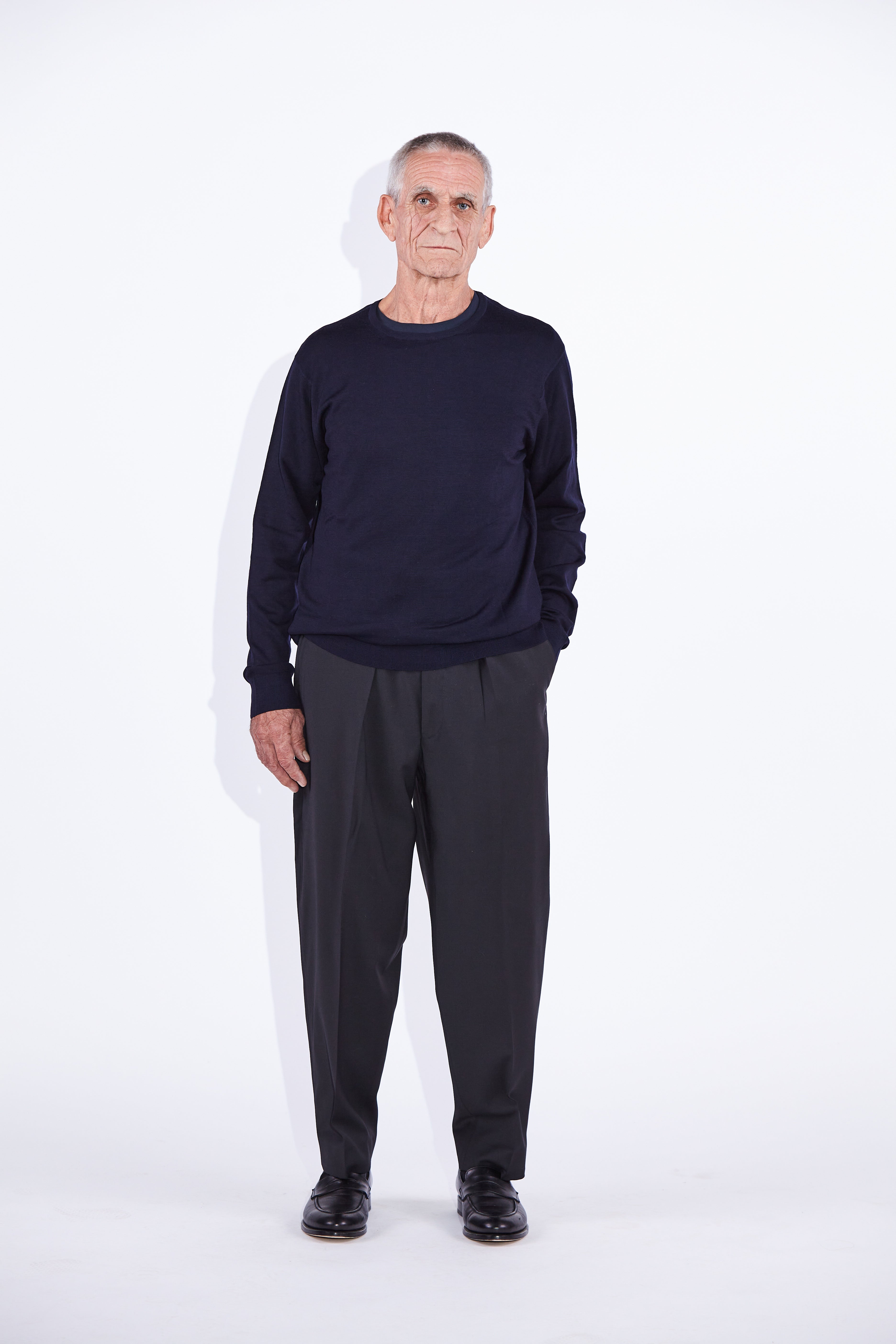 Model wears Casely-Hayford Augustin Navy Merino Wool Crew Neck Jumper. 