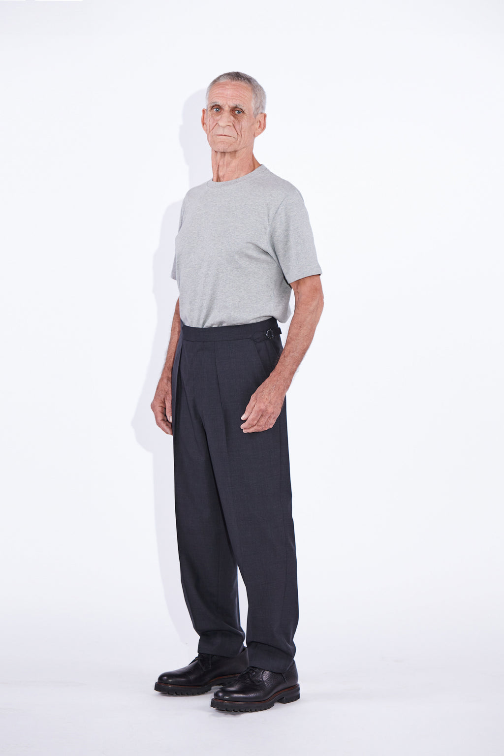 Model wears Casely-Hayford Ezra Anthracite Fresco Relaxed Tapered Leg Wool trousers.