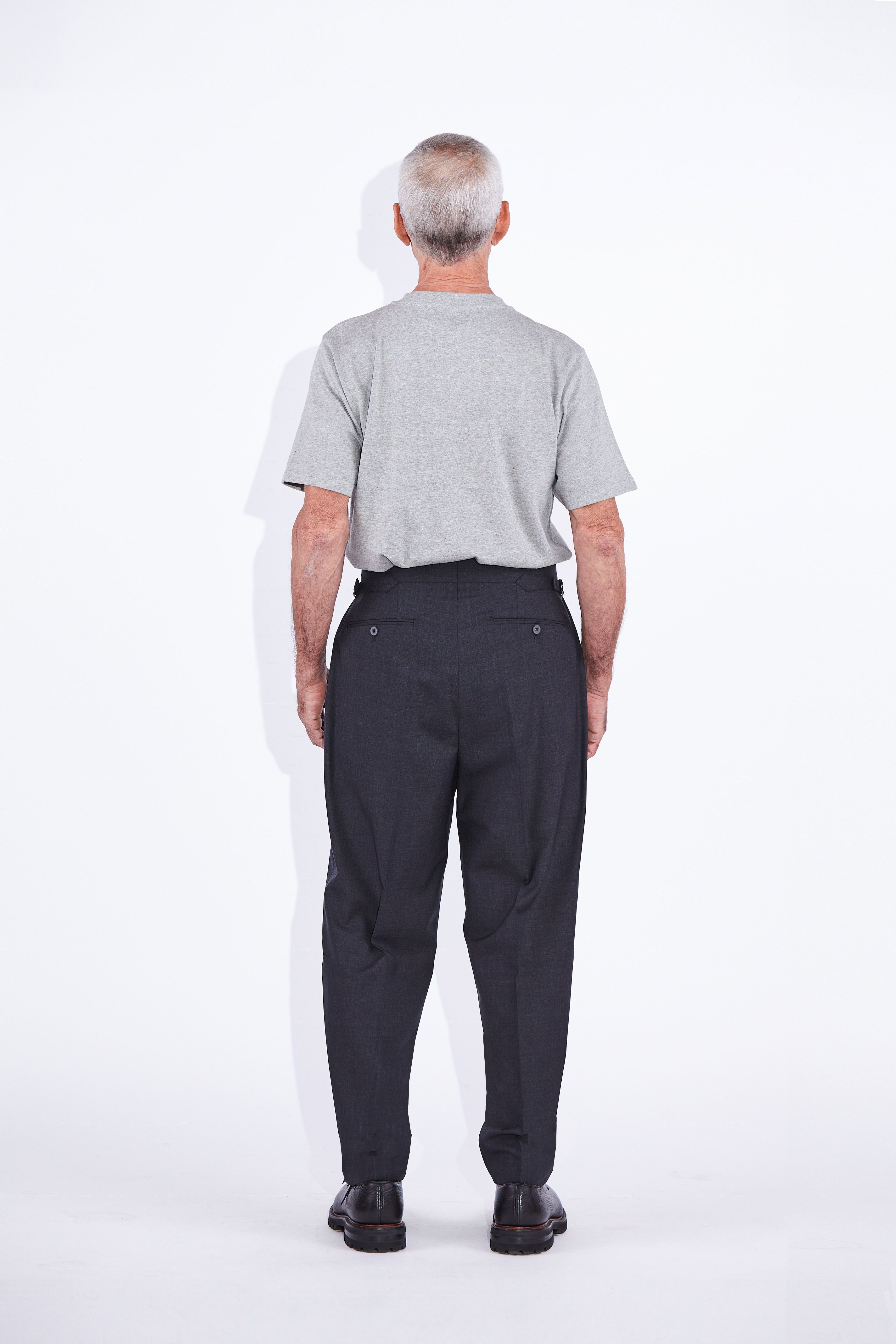 Model wears Casely-Hayford Ezra Anthracite Fresco Relaxed Tapered Leg Wool trousers.