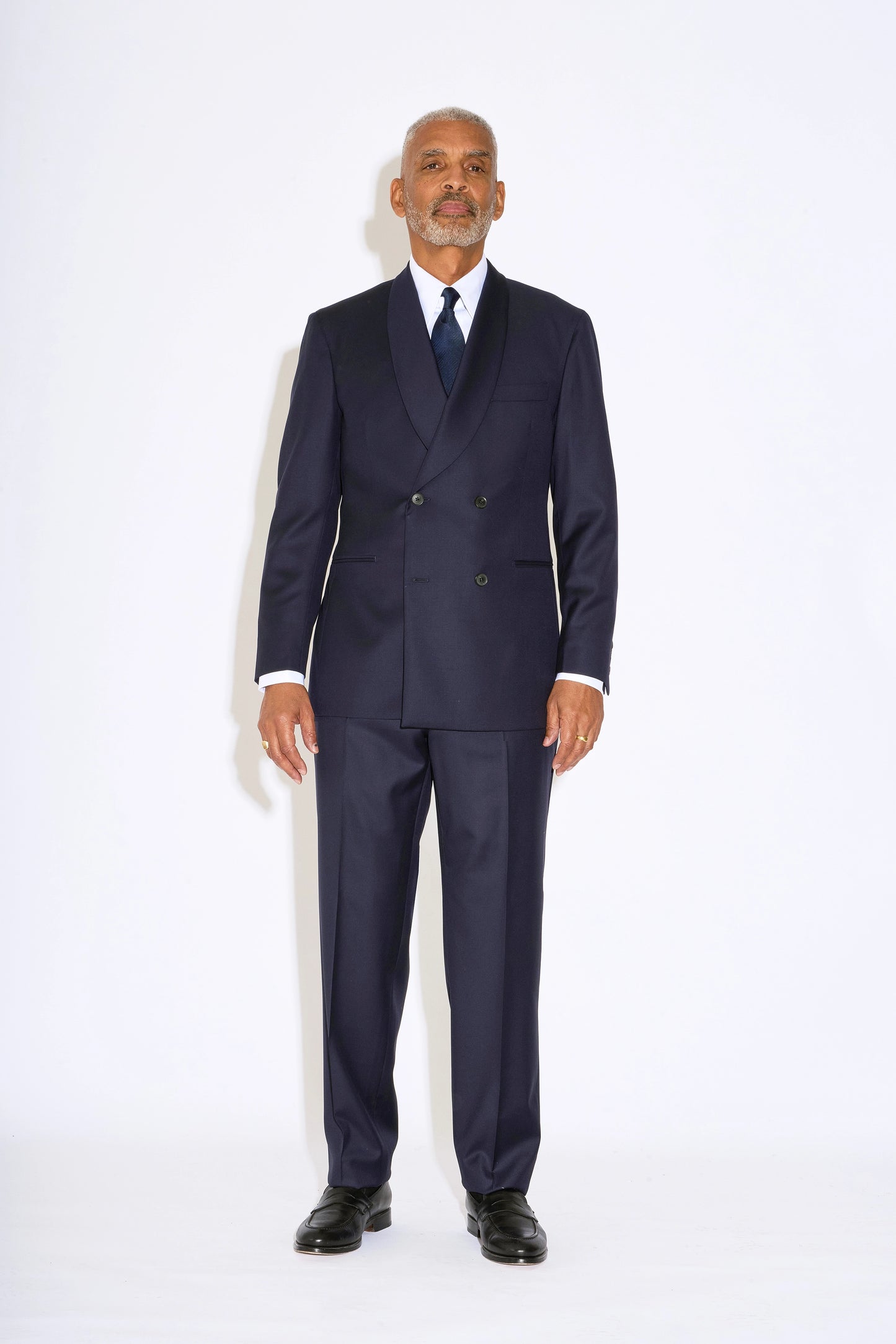 Casely Hayford Hendrix double breasted suit: Model is wearing a navy fitted relaxed shoulder line and soft shawl lapels blazer with matching straight leg trousers