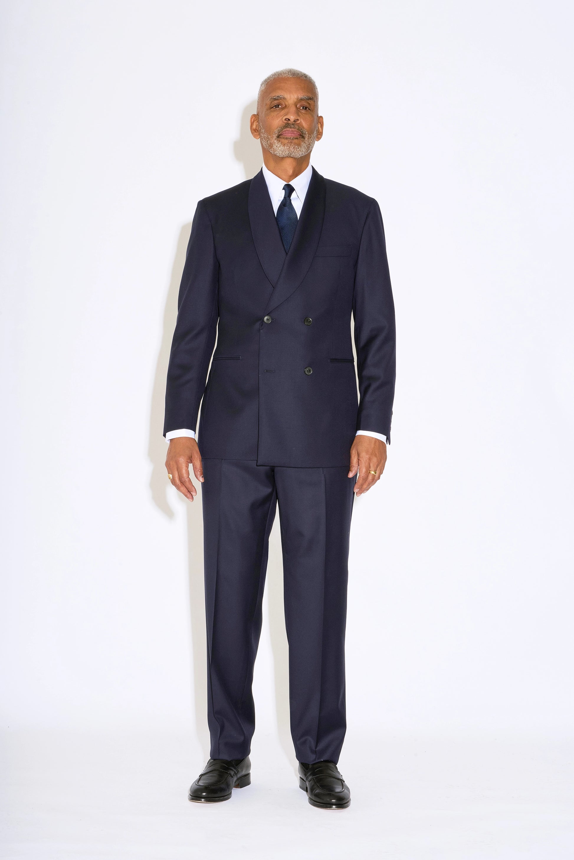 Casely Hayford Hendrix double breasted suit: Model is wearing a navy fitted relaxed shoulder line and soft shawl lapels blazer with matching straight leg trousers