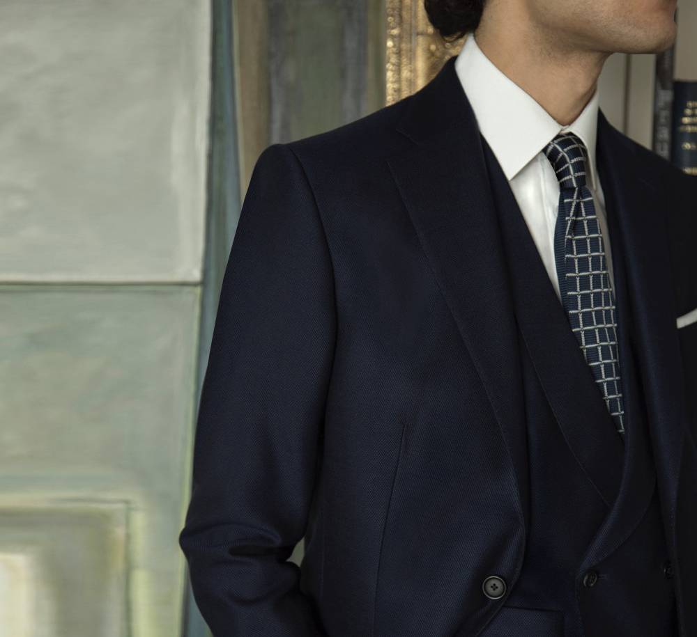 Model wears Casely-Hayford tailored suit on navy. 