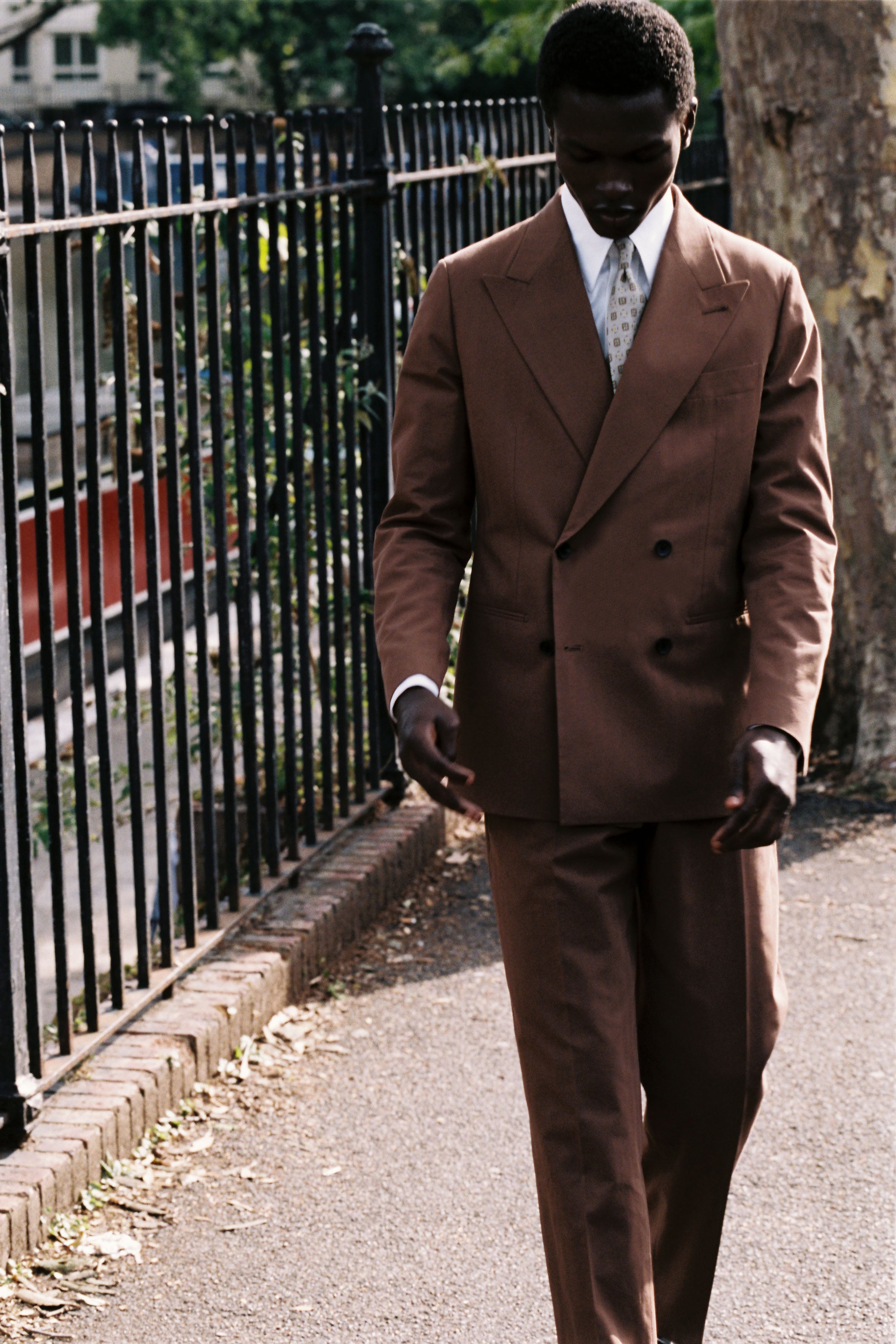 Model wears Casely-Hayford relaxed fit suit in brown.