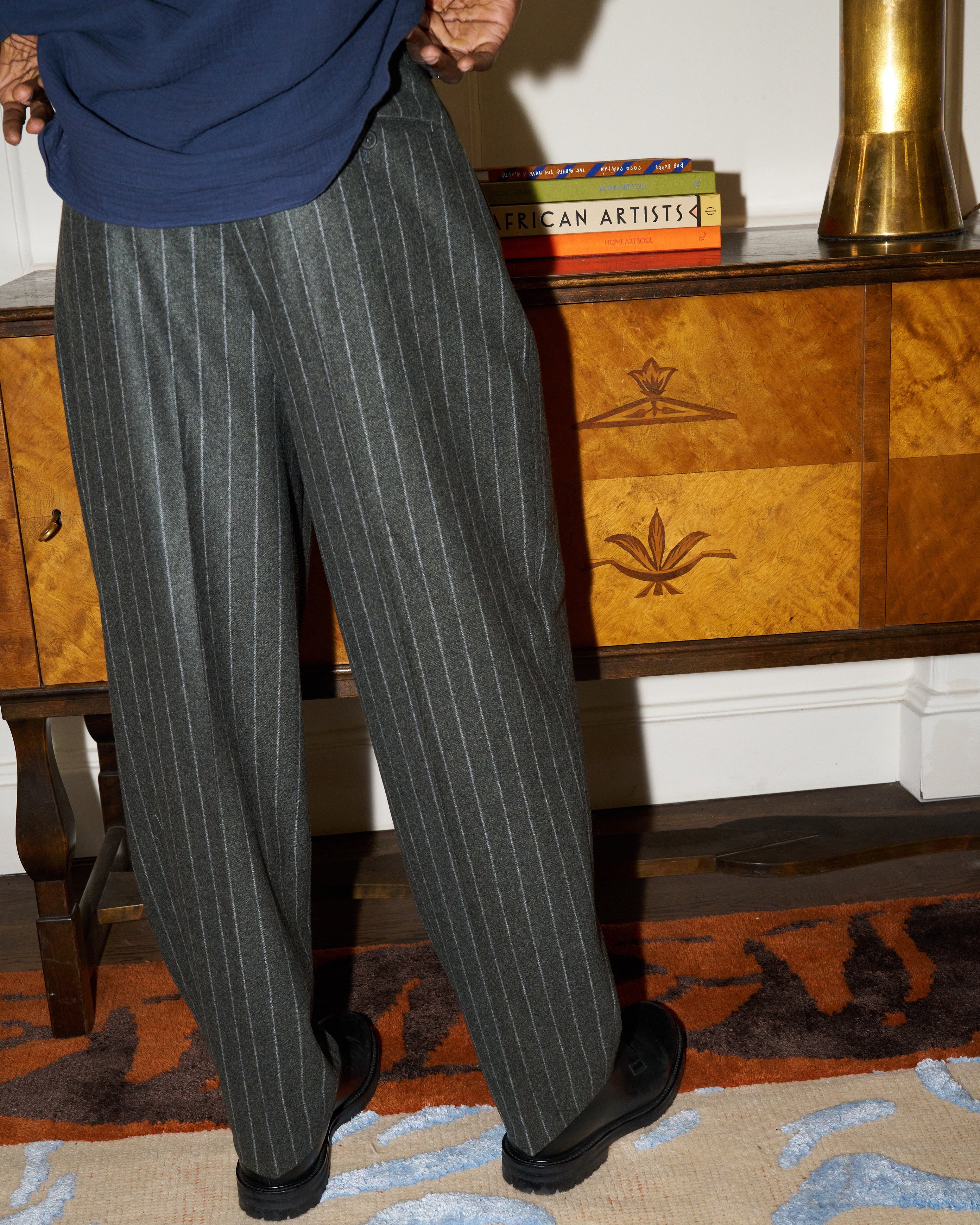 Model wears grey chalk stripe Hannes trousers in a relaxed tailored fit. 
