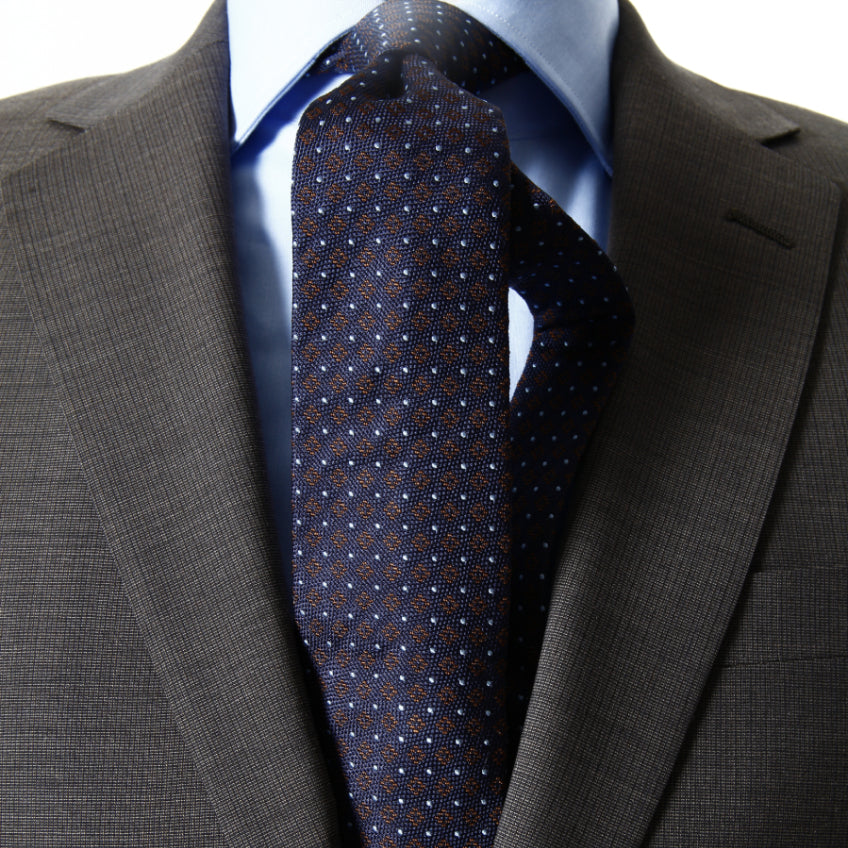 Grey suit worn with a blue shirt and blue and red tie with white dots